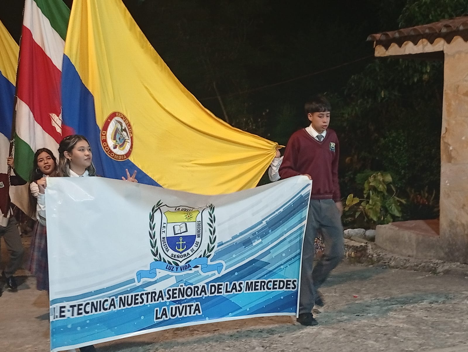 Desfile de faroles con las banderas de la institución